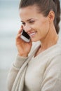 Happy young woman in sweater on beach talking cell phone Royalty Free Stock Photo