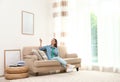 Happy young woman switching on air conditioner with remote control