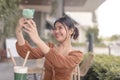 A happy young woman takes a photo of herself on the front camera of her phone and uploads it to her online group chat Royalty Free Stock Photo