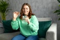 Happy young woman taking a vitamin yellow pill sitting on a couch in the living room at home. Diet. Nutrition. Healthy Royalty Free Stock Photo