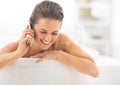 Happy young woman talking cell phone in bathtub Royalty Free Stock Photo