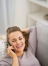 Happy young woman talking cell phone while laying on sofa Royalty Free Stock Photo