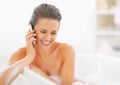 Happy young woman talking mobile phone in bathtub Royalty Free Stock Photo