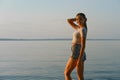 Happy young woman in tank top and denim shorts on the beach at sunset Royalty Free Stock Photo