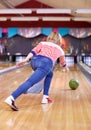 Happy young woman throwing ball in bowling club Royalty Free Stock Photo