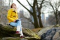 Happy young woman tourist reading a book at Central Park in New York City. Female traveler enjoying views of downtown Manhattan. Royalty Free Stock Photo