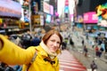 Happy young woman tourist sightseeing at Times Square in New York City. Female traveler enjoying view of downtown Manhattan. Royalty Free Stock Photo