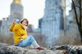 Happy young woman tourist taking pictures at Central Park in New York City. Female traveler enjoying views of downtown Manhattan. Royalty Free Stock Photo