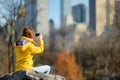 Happy young woman tourist taking pictures at Central Park in New York City. Female traveler enjoying views of downtown Manhattan. Royalty Free Stock Photo