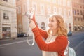 Happy young woman traveler photographer holds camera on European street and takes picture. Summer sun light Royalty Free Stock Photo