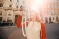 Happy young woman traveler photographer holds camera on European street and takes picture. Summer sun light Royalty Free Stock Photo