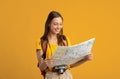 Happy young woman travelling alone, holding city map Royalty Free Stock Photo