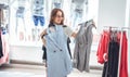 Happy young woman trying on various brand jackets in the shopping mall Royalty Free Stock Photo