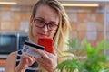 Happy young woman using credit card and phone in kitchen at home Royalty Free Stock Photo