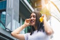 Happy young woman using headphone for listening nice music in city with building background and toothy smile, happiness, smile Royalty Free Stock Photo