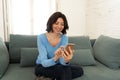 Happy young woman using her smart phone sitting on sofa at home. In leisure and mobile addiction Royalty Free Stock Photo