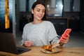 Happy young woman using mobile phone while working with laptop Royalty Free Stock Photo