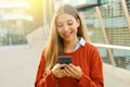 Happy young woman using smart phone on a sunny day in autumn outdoors in modern city Royalty Free Stock Photo