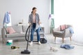 Happy young woman vacuuming her house after party, copy space. Domestic duties concept Royalty Free Stock Photo