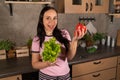 Happy young woman with vegetable on kitchen. Cheerful youthful female enjoying healthy lifestyle while holding bell