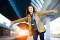 Happy young woman waitng train on the railway station platform.