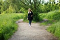 Happy young woman walking in park in jeans and cloak.