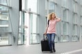 Happy young woman walking with suitcase and cell phone Royalty Free Stock Photo