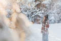 Young woman walks in forest among snow covered pine trees against snowflakes background Royalty Free Stock Photo