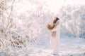 Happy young woman walks in forest among snow covered trees against background of snowflakes Royalty Free Stock Photo