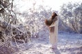 Happy young woman walks in forest among snow covered trees in sunny winter day Royalty Free Stock Photo