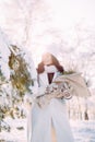 Happy young woman walks in winter forest among trees in sunny day Royalty Free Stock Photo