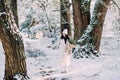 Happy young woman walks in winter forest among trees in sunny day Royalty Free Stock Photo