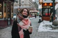 Happy young woman in warm clothing standing on city street