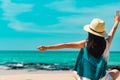 Happy young woman wear straw hat sit and raised hand at sand beach. Relaxing and enjoy holiday at tropical paradise beach Royalty Free Stock Photo