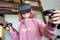 Happy young woman wear vr headset hold controllers play virtual reality game.