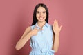 Happy young woman wearing beautiful engagement ring on pink background