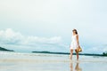 Happy young woman wearing beautiful white dress walking on the beach Royalty Free Stock Photo