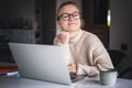 Happy young woman wearing glasses sitting at home and using laptop, online work and education Royalty Free Stock Photo