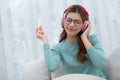 Happy young woman wearing headphones listening music while sitting on sofa with fun and enjoy in the living room. Royalty Free Stock Photo