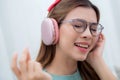 Happy young woman wearing headphones listening music while sitting on sofa with fun and enjoy in the living room. Royalty Free Stock Photo