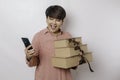 A happy young woman is wearing a pink shirt while holding a stack of presents and her smartphone Royalty Free Stock Photo