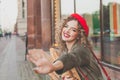 Happy young woman wearing red french beret waving hello