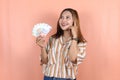 young asian woman holding cash money in Indonesian rupiah and thingking