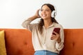 Happy Young Woman Wearing Wireless Headphones Listening Music On Smartphone At Home Royalty Free Stock Photo