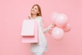 Happy young woman, in a white dress, with bags in hands and balloons, on a pink background. shopping concept Royalty Free Stock Photo