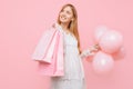 Happy young woman, in a white dress, with bags in hands and balloons, on a pink background. shopping concept Royalty Free Stock Photo