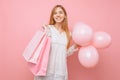 Happy young woman, in a white dress, with bags in hands and balloons, on a pink background. shopping concept Royalty Free Stock Photo