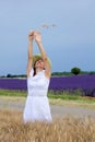 Happy young woman in white dress standing in cornfield.