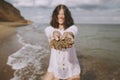 Happy young woman in white shirt holding wet sand in hands on beach. Funny tanned girl relaxing on seashore. Summer vacation. Royalty Free Stock Photo