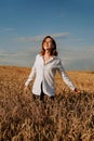 Happy young woman in a white shirt in a wheat field. Sunny day. Royalty Free Stock Photo